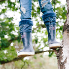Puddleflex Fleece Lined Wellies Navy: A child in ripped jeans sits in a tree, wearing blue wellies with quilted fleece lining.